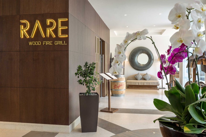 Entrance of Rare Wood Fire Grill with floral decor.