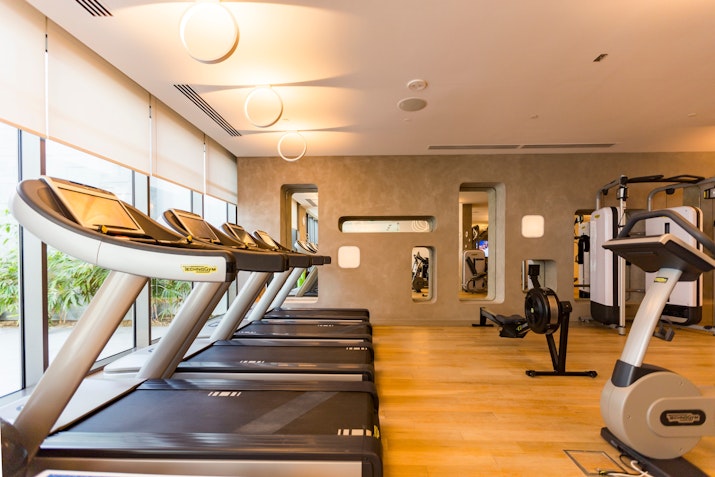 Tone Gym at Nikki Beach Resort & Spa Modern gym with treadmills and exercise equipment near large windows.