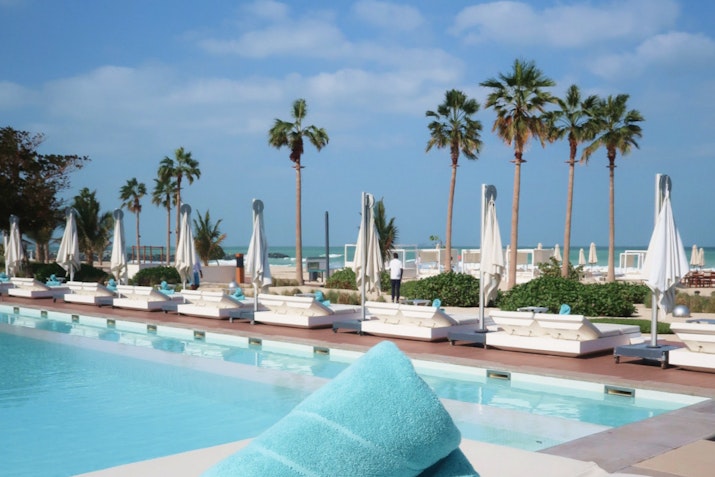 Nikki Beach Resort & Spa Poolside with white loungers, umbrellas, and palm trees by the beach.