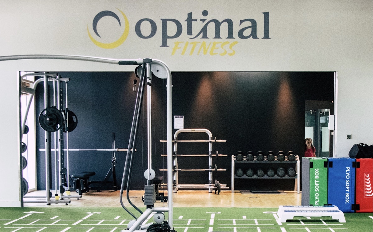 Interior of Optimal Fitness gym featuring exercise equipment and a logo