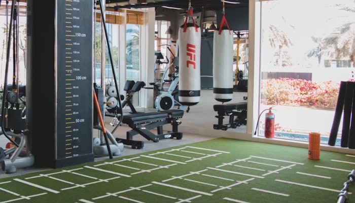 Optimal Fitness Interior view of a gym with exercise equipment, UFC punching bags, and a turf training area.