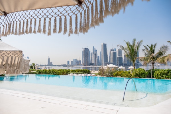 A stylish pool area with lounge chairs and a view of the Dubai skyline.