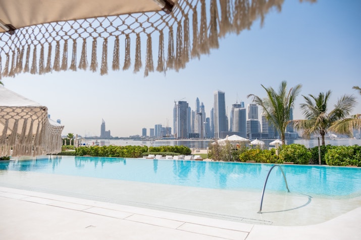 A stylish pool area with lounge chairs and a view of the Dubai skyline.