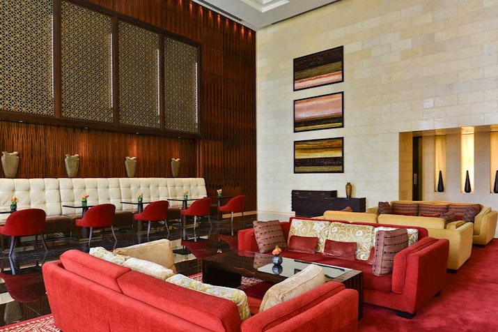Raffles Dubai Stylish lounge with comfortable seating, wooden accents, and decorative art on the walls.