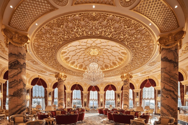 Luxurious dining room with a detailed gold ceiling and elegant chandeliers.