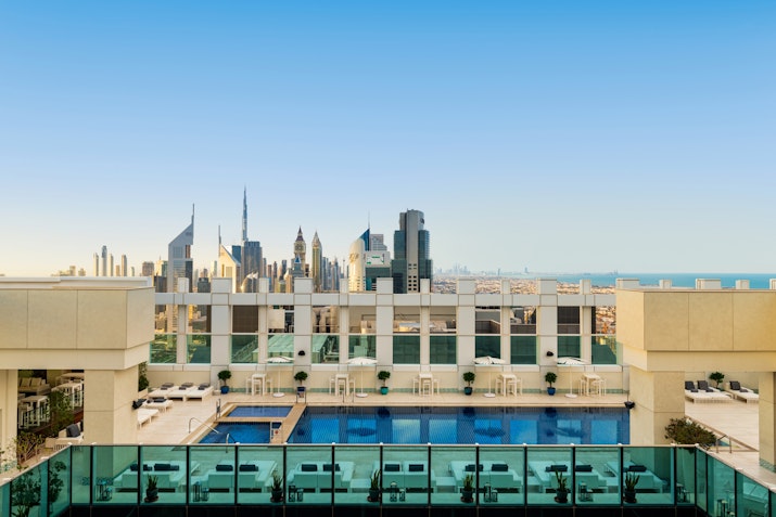 Sheraton Grand Hotel Dubai Rooftop pool with a stunning view of the skyline, featuring iconic buildings like the Burj Khalifa, under a clear blue sky.