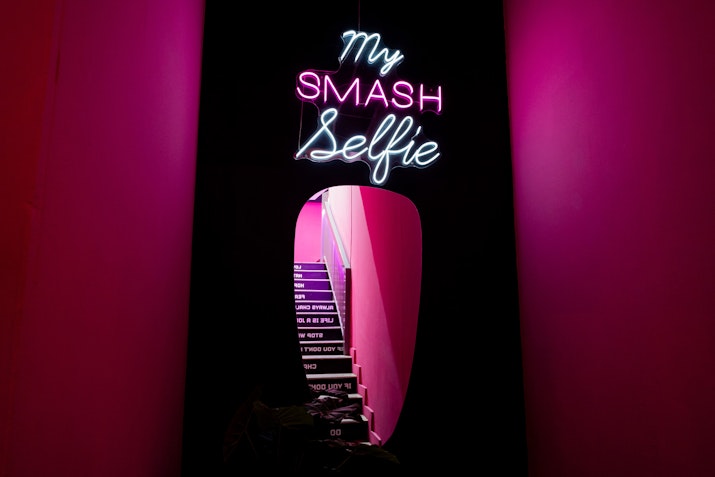 Mirror on a black and pink wall with a neon sign above it