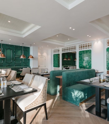 Sofitel Al Hamra Beach Resort An elegant restaurant interior featuring stylish seating arrangements, green accents, and modern light fixtures, creating a sophisticated dining atmosphere.