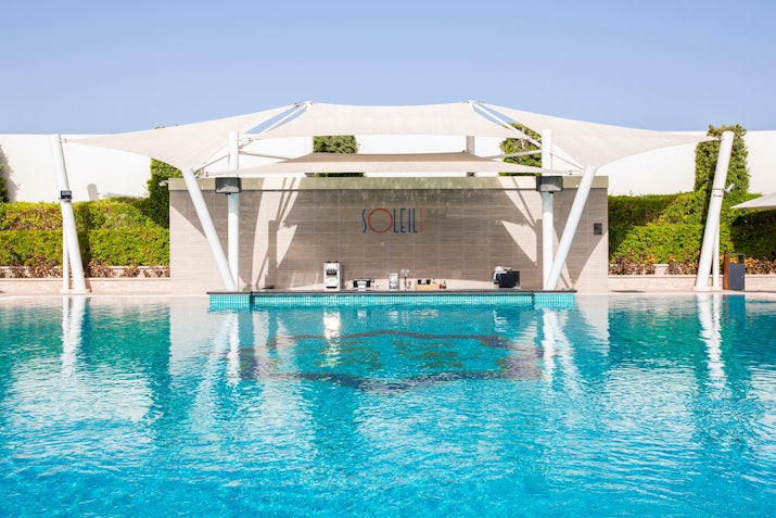 Pool with a bar area under a large white canopy.