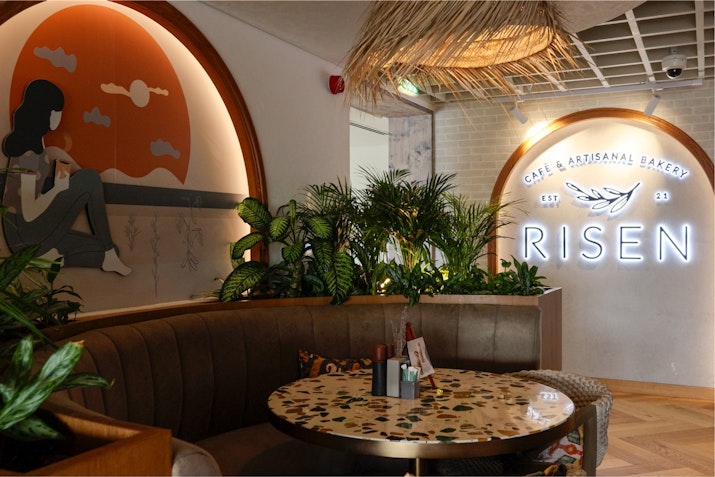 Cozy cafe interior featuring a curved seating area with a decorative table, and lush plants