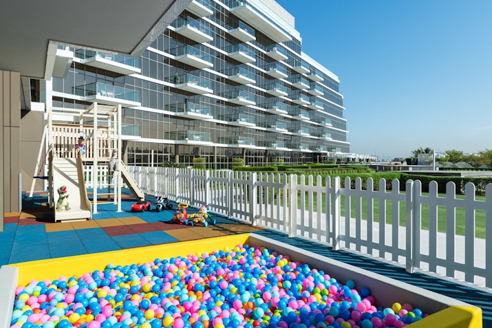 Children's play area with ball pit and playground near a modern building.