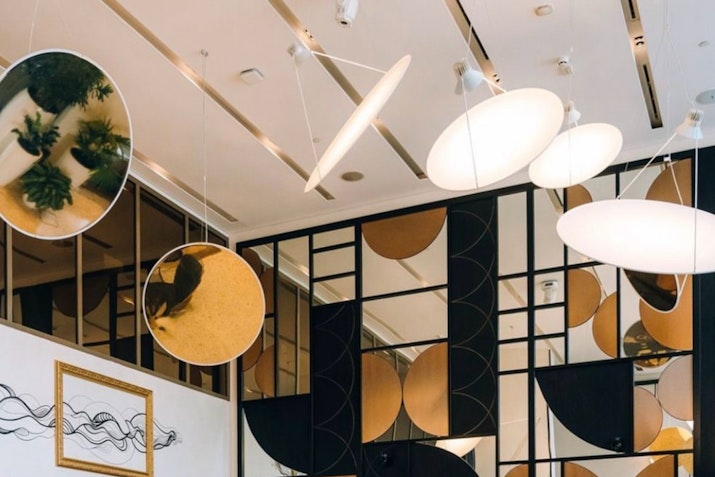 Modern ceiling decor with circular mirrors and abstract lighting fixtures.