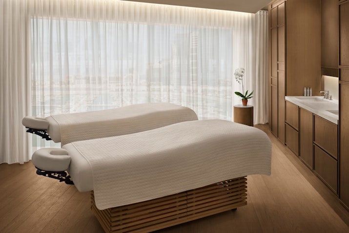 Two massage beds in a spa room with large windows and natural light.