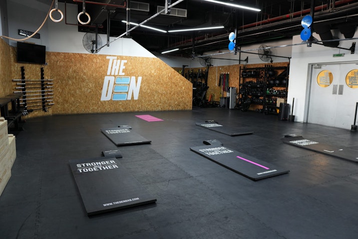 Functional training gym space with a black floor, bright lights, and an industrial aesthetic