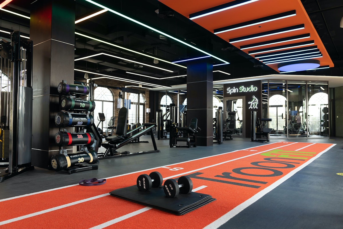 A modern gym interior featuring weightlifting equipment, dumbbells, and a running track