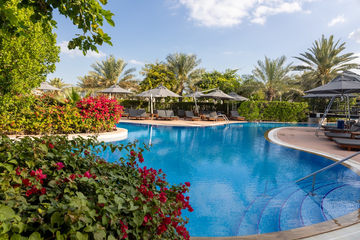 Tranquil pool surrounded by lush greenery and shaded loungers.