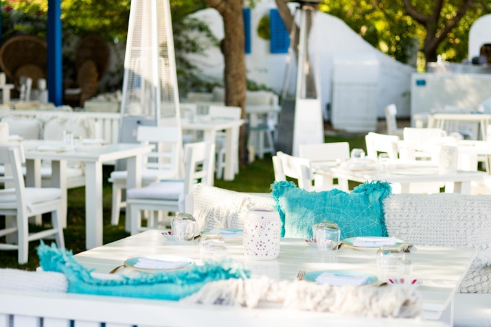 Fish at The Westin Dubai Mina Seyahi Beach Resort & Marina Outdoor dining area with white tables, turquoise cushions, and greenery.