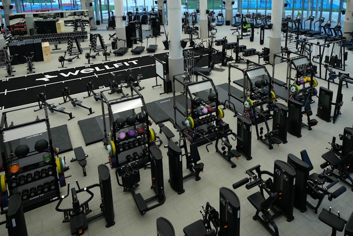 Birds-eye view of gym floor featuring a range of strength and resitance machines, plus olympic weight lifting platforms and free weights