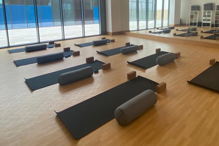 Peaceful yoga studio at Jumeirah Park Pavilion with natural lighting, floor-to-ceiling windows, yoga mats, and props