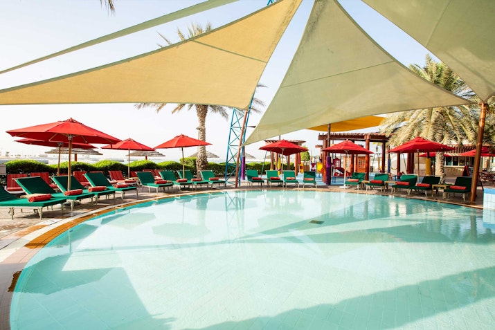 Shaded pool area with red loungers and umbrellas