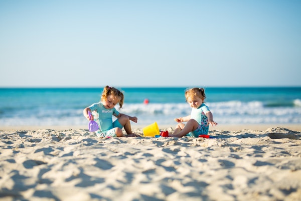 Two young children playing with toys on a sandy beach