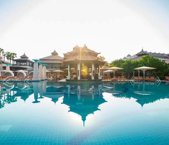 Anantara The Palm Dubai Resort Pool with a reflective surface, surrounded by resort buildings and palm trees, set against a sunny sky