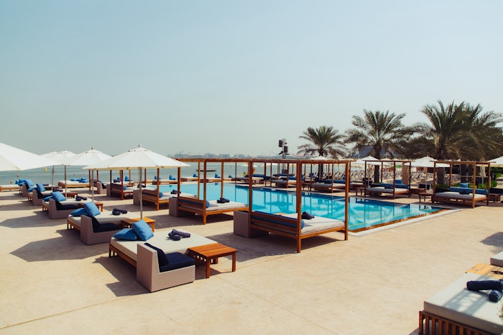 Poolside seating with lounge chairs and umbrellas overlooking a serene pool.