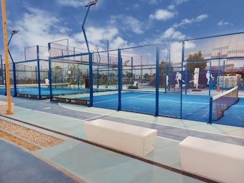 Paddle courts with blue flooring and protective fencing.