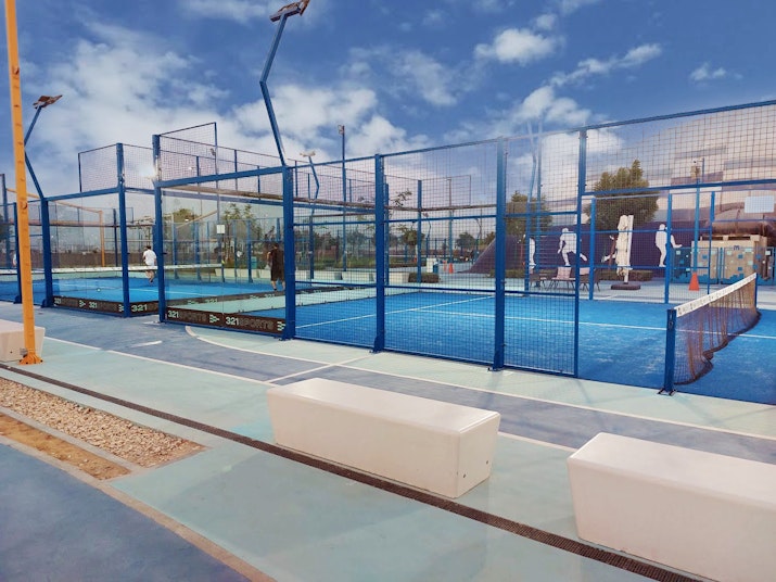 Paddle courts with blue flooring and protective fencing.