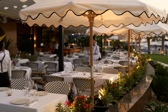 Outdoor restaurant seating with striped umbrellas and elegant table settings
