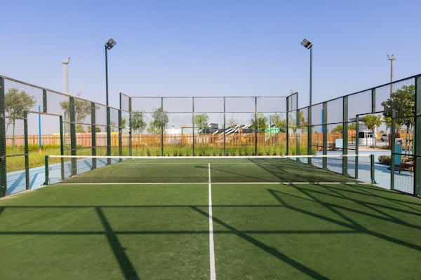 Outdoor tennis or padel court with surrounding fencing and clear blue sky
