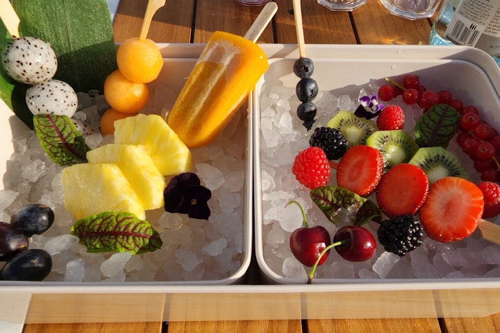 A platter of assorted fresh fruits, including pineapple, berries, cherries, and dragon fruit, arranged on ice.