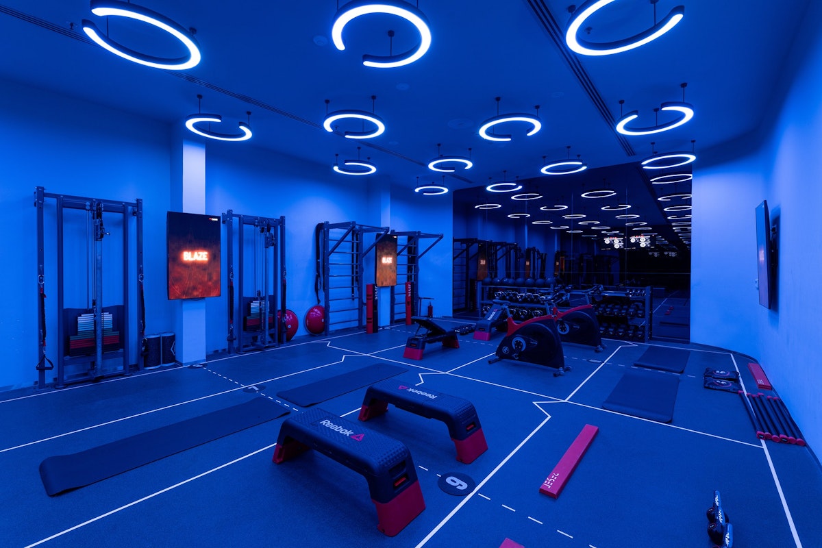A gym with modern blue lighting, fitness equipment, and workout benches