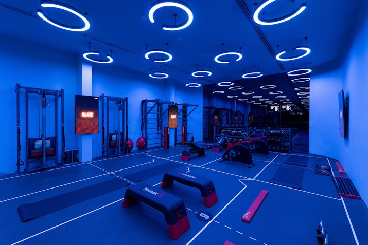 A gym with modern blue lighting, fitness equipment, and workout benches