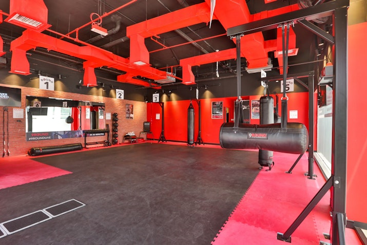 A boxing gym with red decor, punching bags, and workout equipment.