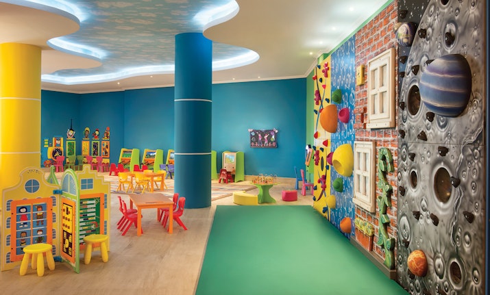 Vibrant indoor play area with colorful furniture, climbing wall, and playful designs.
