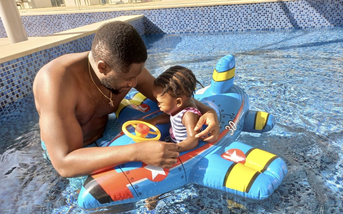 Father and child playing in the pool on a toy airplane float.