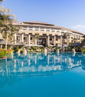 Sofitel Dubai The Palm A beautiful resort pool surrounded by tropical landscaping and a luxurious hotel.