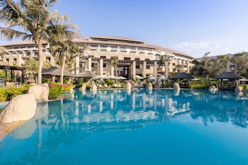 A beautiful resort pool surrounded by tropical landscaping and a luxurious hotel.