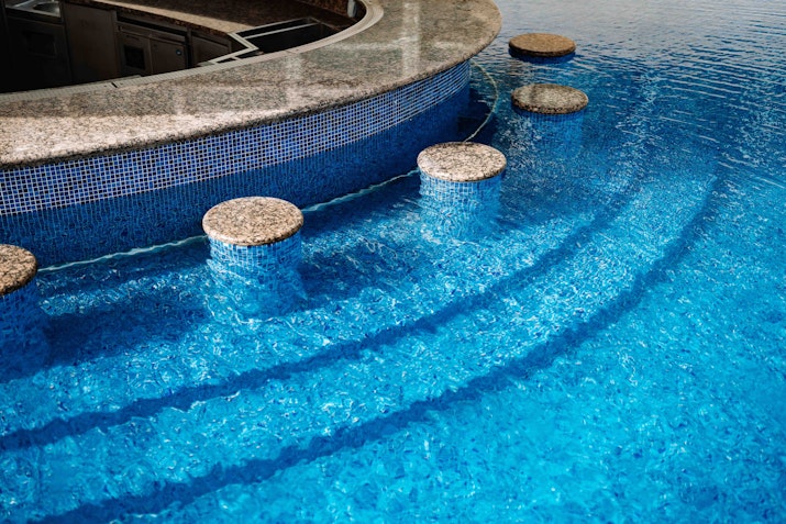 Submerged stools lining a swim up pool bar
