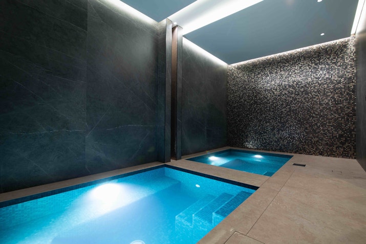 Small plunge pools in a dimly lit room with grey tiles walls