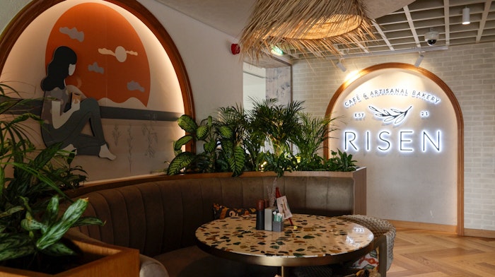 A stylish seating area, featuring greenery, a mural, and warm lighting.