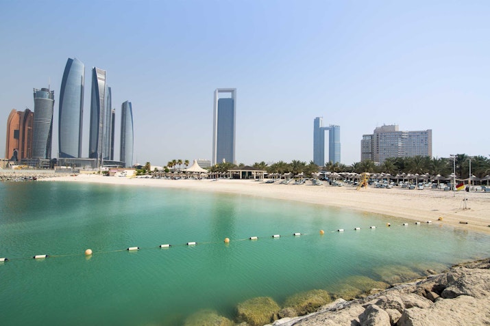 InterContinental Abu Dhabi A beach with clear water and skyscrapers in the background.