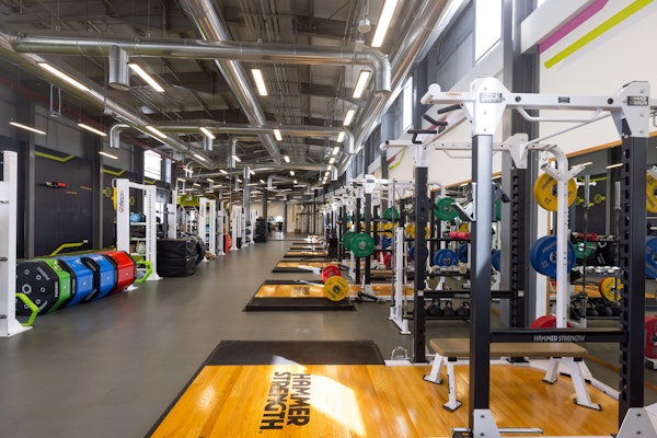 Well-equipped gym with weightlifting stations and colorful kettlebells.