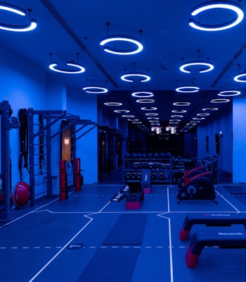 Reset Fitness A modern gym interior illuminated with blue lights, featuring exercise equipment and a spacious workout area
