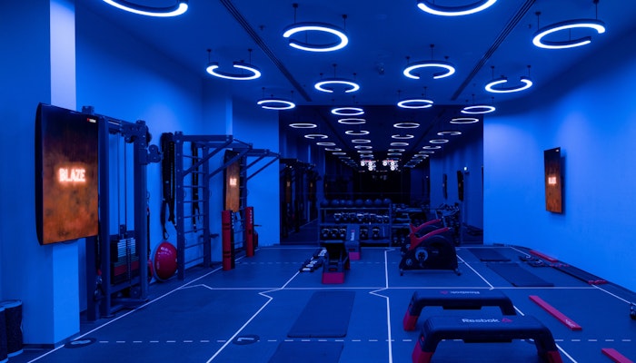Reset Fitness A modern gym interior illuminated with blue lights, featuring exercise equipment and a spacious workout area