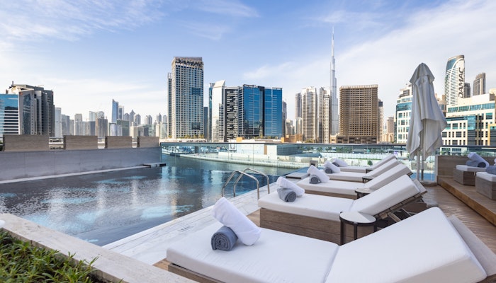 Hyde Hotel, Business Bay A rooftop pool with lounge chairs overlooking a city skyline, including the Burj Khalifa.