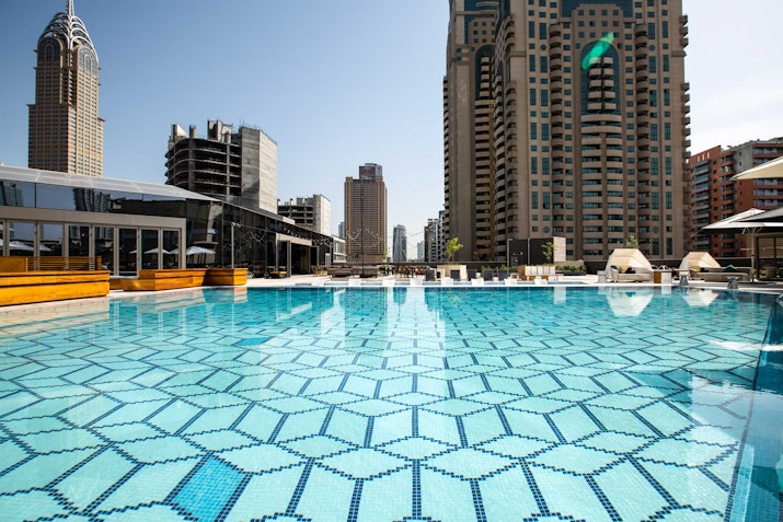 Rooftop pool with patterned tiles and city skyline view