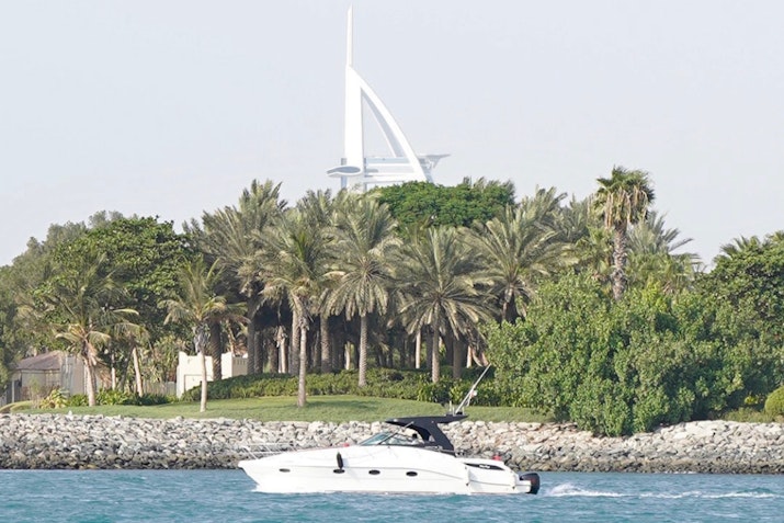 Views that make your heart skip a beat: yacht on the water with lush greenery and Burj Al Arab in the background.