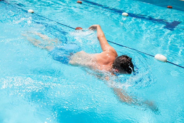 A person swimming in a pool performing the backstroke.